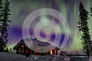 Polar arctic Northern lights Aurora Borealis activity over wooden hoseu in winter Finland, Lapland photo