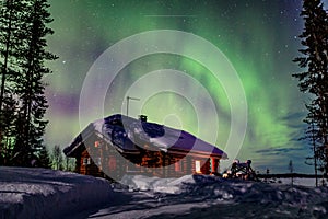 Polar arctic Northern lights Aurora Borealis activity over the wooden house in winter Finland, Lapland