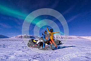 The polar arctic snowmobile Northern lights aurora borealis sky star in Norway Svalbard in Longyearbyen city man mountains