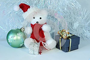Polar bear wearing a hat and a red scarf posed next to gifts with shiny knots on a Christmas holiday decor