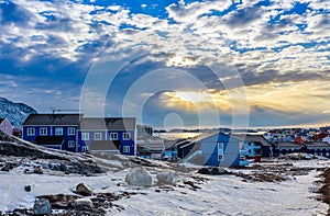 Polar sunset over Inuit houses on the rocky hills with snow, Nuuk city, Greenland photo