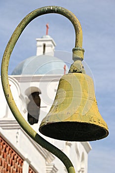 Pole of an antique bell frames the steeple of an old church