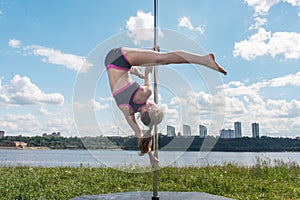 Pole dance fit woman exercising with pylon outdoors