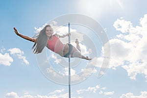 Pole dance fit woman exercising with pylon outdoors