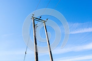 Pole of electric power cable line against blue sky