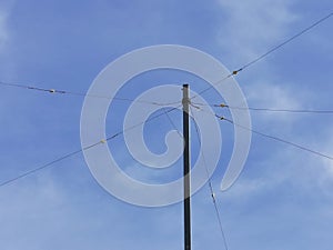 Pole with electrical wires against a blue sky