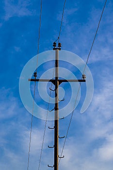 Pole with electrical wires on blue sky and white clouds background.