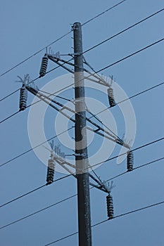 Pole of a high-voltage power line covered with hoarfrost in frosty weather