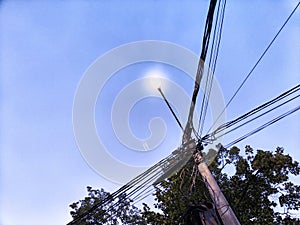 A pole with a lantern and a lot of wires against the background of the evening or night sky. Lighting and power line