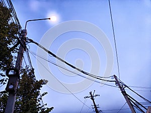 A pole with a lantern and a lot of wires against the background of the evening or night sky. Lighting and power line