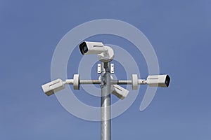 Pole mounted security cameras against blue sky
