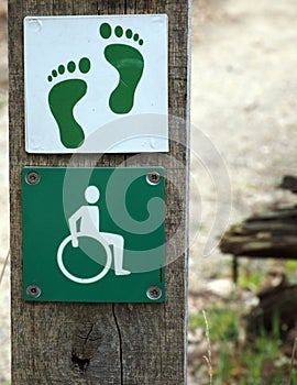 Pole with signs for disable hiking track and bare feet path