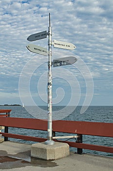 Pole in Toronto shows distances and direction to Halifax, Niagara Falls, Vancouver and the North Pole on a cloudy day by lake