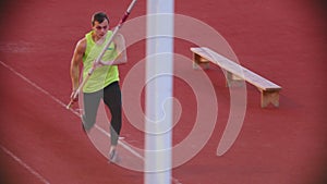 Pole vault training on the stadium - an athletic man performing his jump attempt