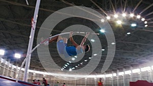 Pole vault training in the stadium - a young man jumping over the bar