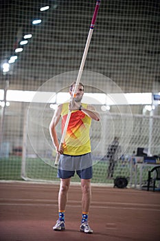 Pole vaulting - man in yellow shirt is standing with a pole in hands