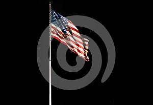 Pole with waving Old Glory American flag isolated on black, copy space