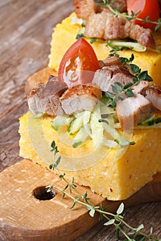Polenta with bacon, vegetables on wooden board vertical