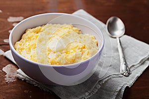 Polenta with butter and cheese in plate on rustic table