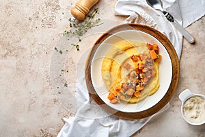 Polenta with butter, pumpkin, garlic, savory and parmesan cheese in white bowl on light concrete background. Traditional Basic