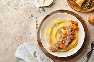 Polenta with butter, pumpkin, garlic, savory and parmesan cheese in white bowl on light concrete background. Traditional Basic Ita