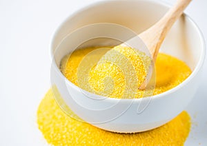 Polenta or Cornmeal Flour. Ground Dried Corn or Corn Grits in a white bowl and wooden spoon