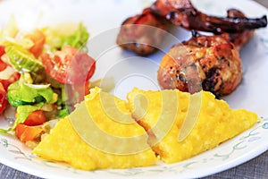 Polenta or Mamaliga, baked chicken legs and salad in fancy plate. Traditional food and culinary culture specific for Balkan