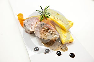 Polenta, roasted pork and rosemary with balsamic reduction on a white plate