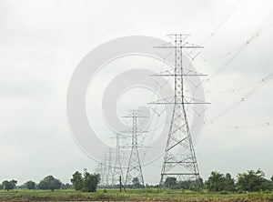 Poles and high voltage transmission lines on sky and clouds background