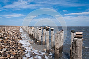 Poles beside ocean with stones put on top