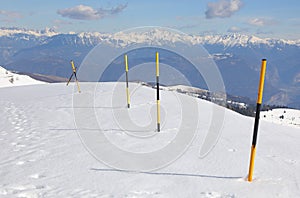 poles painted yellow and black stuck in the snow to delimit the limit of the ravine in the mountains