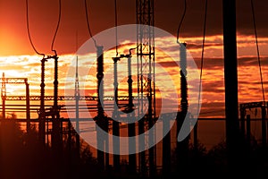 Poles at a power plant at sunset as a background