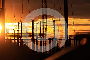 Poles at a power plant at sunset as a background