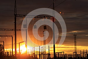 Poles at a power plant at sunset as a background