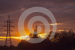 Poles at a power plant at sunset as a background