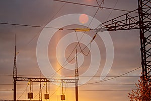 Poles at a power plant at sunset as a background