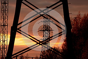 Poles at a power plant at sunset as a background