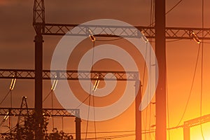 Poles at a power plant at sunset as a background