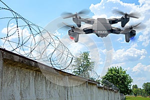 Police drone patrols the area across the sky. Guarding the wall with barbed wire drone with blue and red beacon