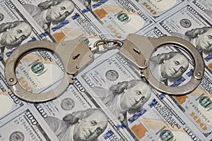 Police handcuffs against a hundred dollar bills USA. Concept violation of the law, corruption, financial fraud.