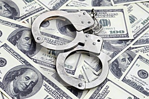 Police handcuffs lie on a lot of dollar bills. The concept of illegal possession of money, illegal transactions with US dollars.