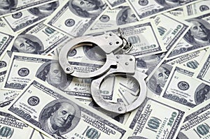 Police handcuffs lie on a lot of dollar bills. The concept of illegal possession of money, illegal transactions with US dollars.