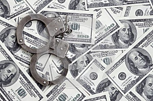 Police handcuffs lie on a lot of dollar bills. The concept of illegal possession of money, illegal transactions with US dollars.