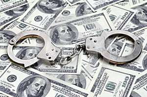 Police handcuffs lie on a lot of dollar bills. The concept of illegal possession of money, illegal transactions with US dollars.