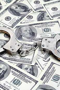 Police handcuffs lie on a lot of dollar bills. The concept of illegal possession of money, illegal transactions with US dollars.