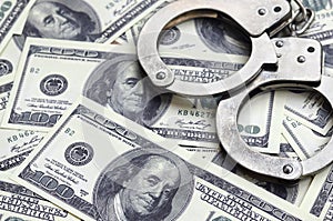 Police handcuffs lie on a lot of dollar bills. The concept of illegal possession of money, illegal transactions with US dollars.