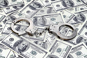 Police handcuffs lie on a lot of dollar bills. The concept of illegal possession of money, illegal transactions with US dollars.