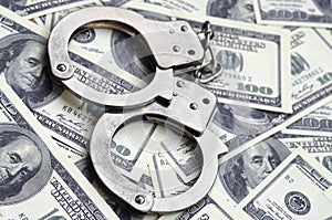 Police handcuffs lie on a lot of dollar bills. The concept of illegal possession of money, illegal transactions with US dollars.