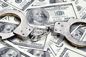 Police handcuffs lie on a lot of dollar bills. The concept of illegal possession of money, illegal transactions with US dollars.