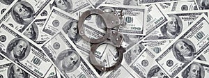 Police handcuffs lie on a lot of dollar bills. The concept of illegal possession of money, illegal transactions with US dollars.